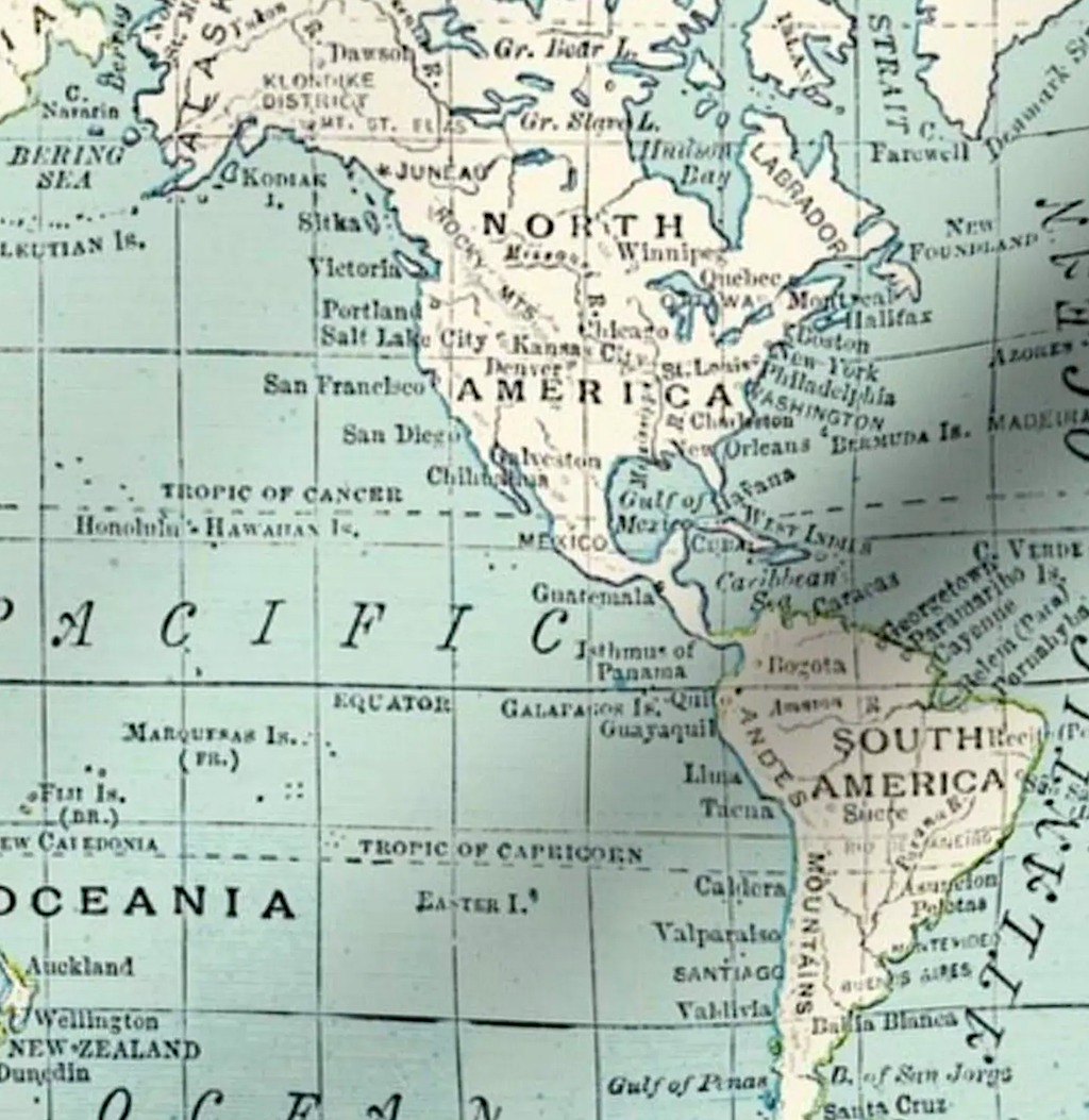 A close-up of a vintage map showing parts of North and South America, with pale blue oceans, cream landmasses, and black place names.