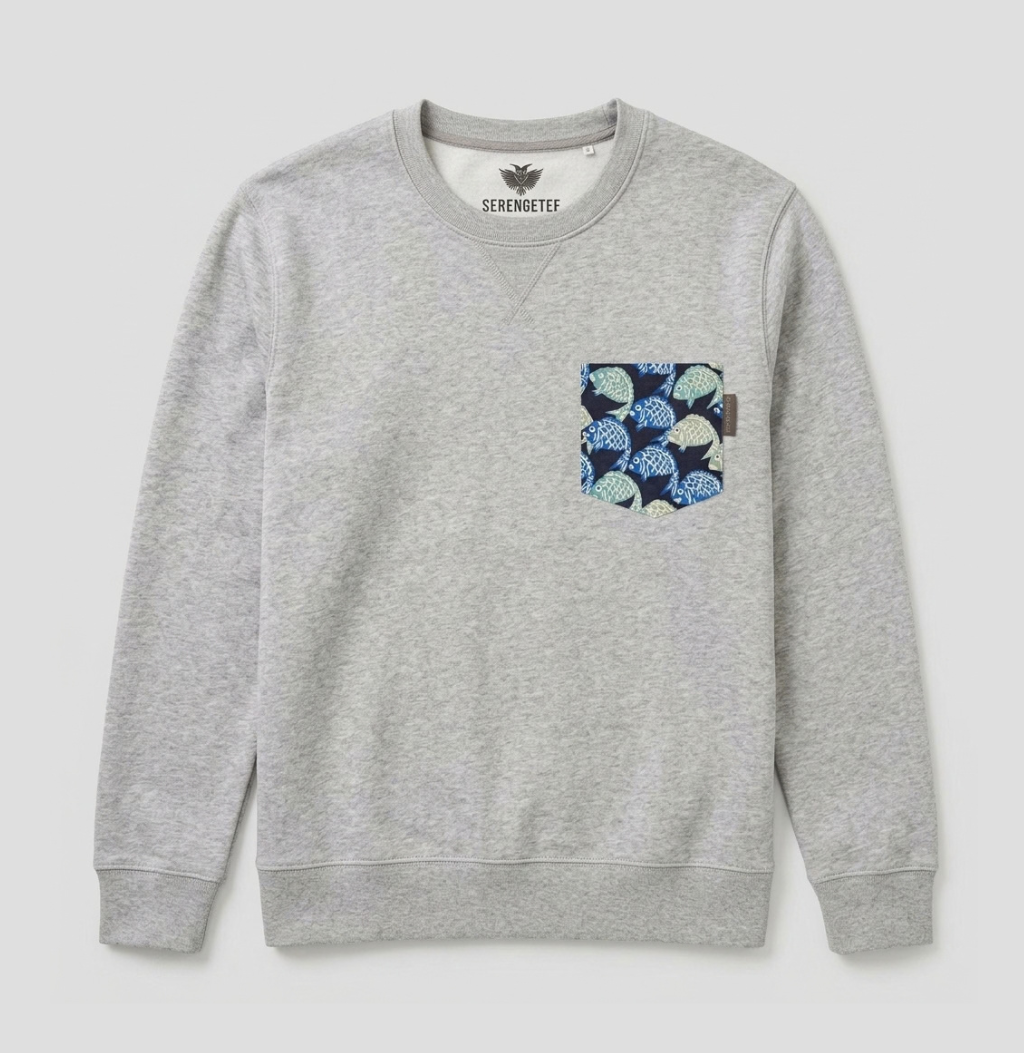 A heather gray crewneck sweatshirt by Serenaded, featuring a patterned chest pocket with blue, navy, and cream fish-scale motifs, shown flat on a light gray background.