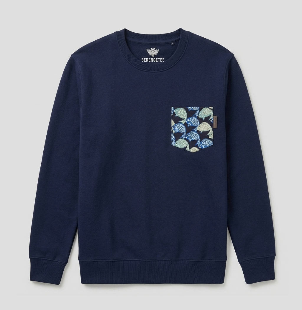 A navy blue crewneck sweatshirt with a patterned chest pocket featuring blue, green, and beige fish-scale motifs, shown against a light gray background.