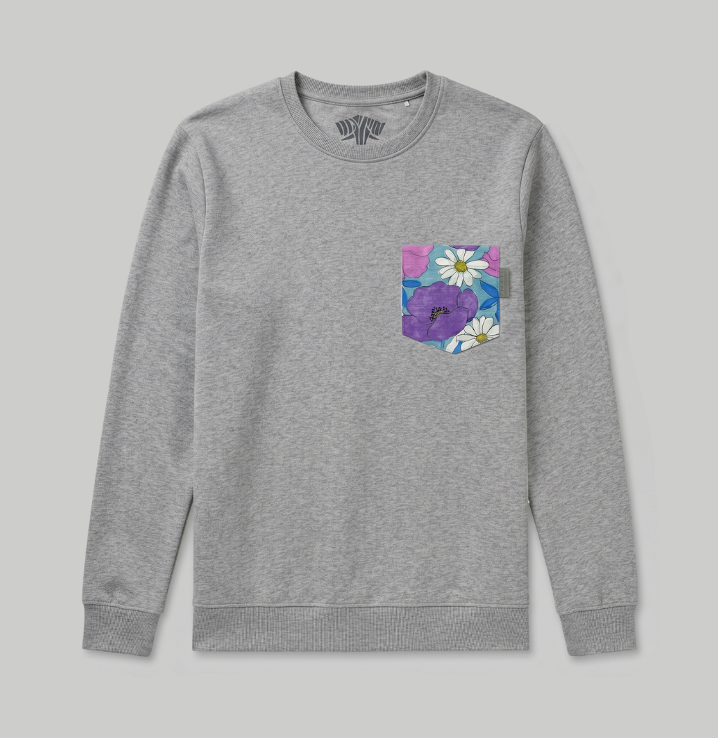 A heather gray crewneck sweatshirt with a floral pocket on the left chest, featuring purple flowers and white daisies on a blue background, shown against a solid gray backdrop.
