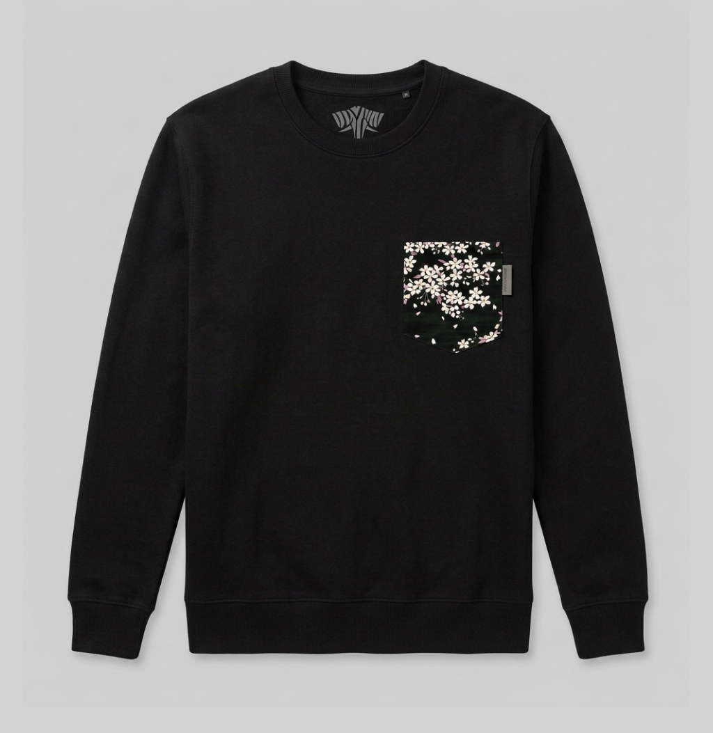 A black crewneck sweatshirt with a chest pocket featuring a white and green floral pattern, displayed flat against a light gray background.