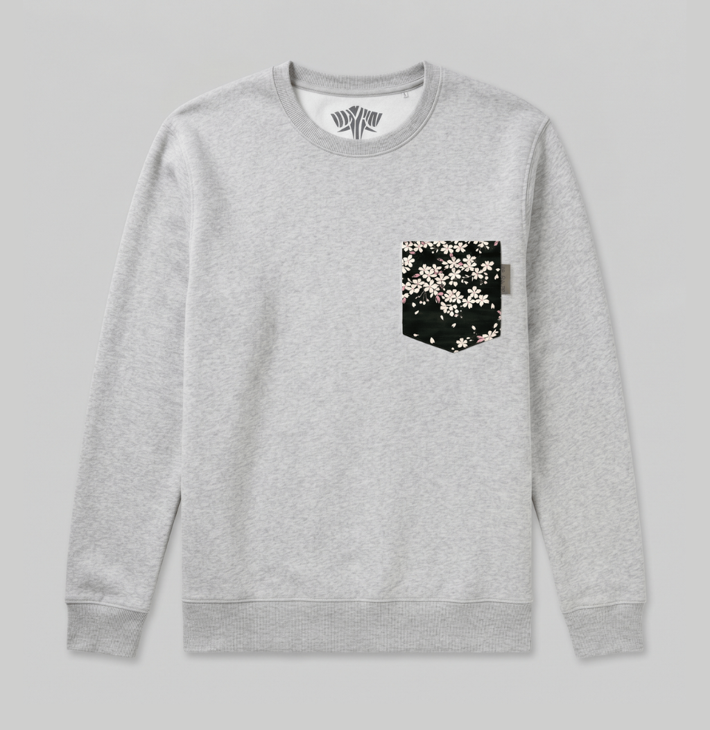 A light gray heather crewneck sweatshirt with a black chest pocket decorated with a white cherry blossom pattern, shown against a solid gray background.