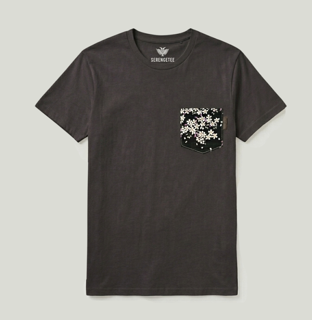 A dark charcoal gray crewneck t-shirt with a chest pocket featuring a black and white floral pattern, shown flat on a light gray background. The brand name 'SIRIOMETRIE' is printed inside the collar.