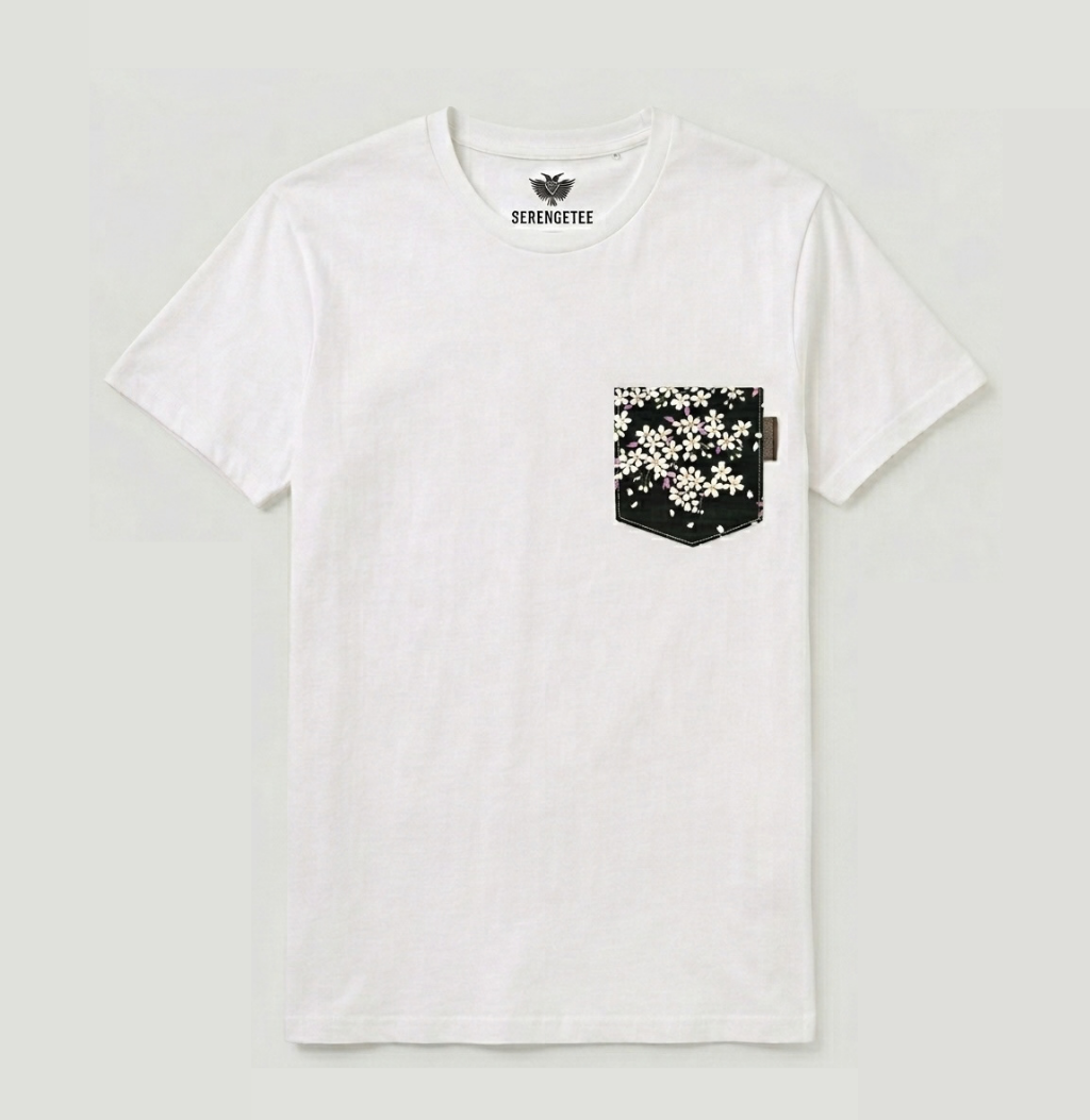A white crewneck pocket t-shirt by Serengetee, featuring a black chest pocket with a white dalmatian-style spot pattern and a black brand logo printed inside the collar.