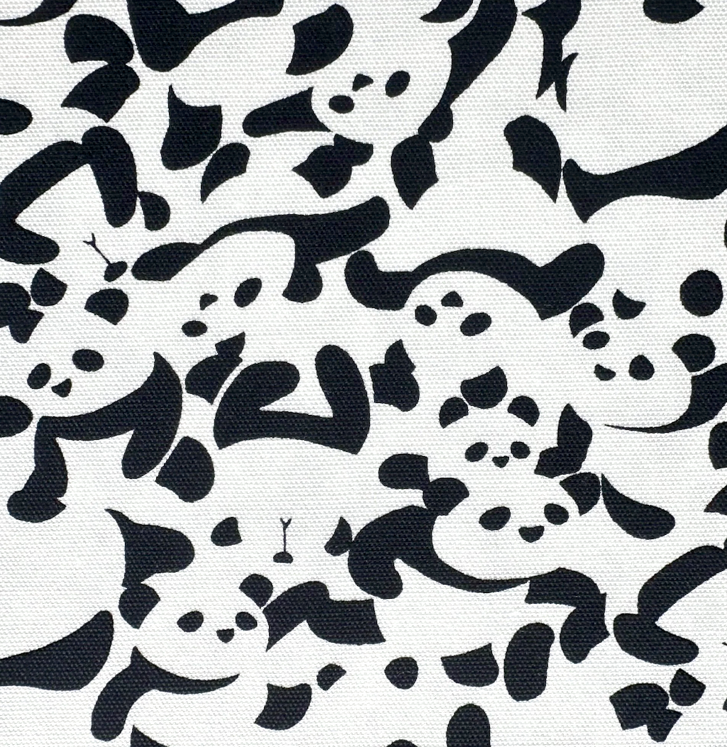 A close-up of a fabric pattern featuring black abstract cartoon-like shapes on a white background.